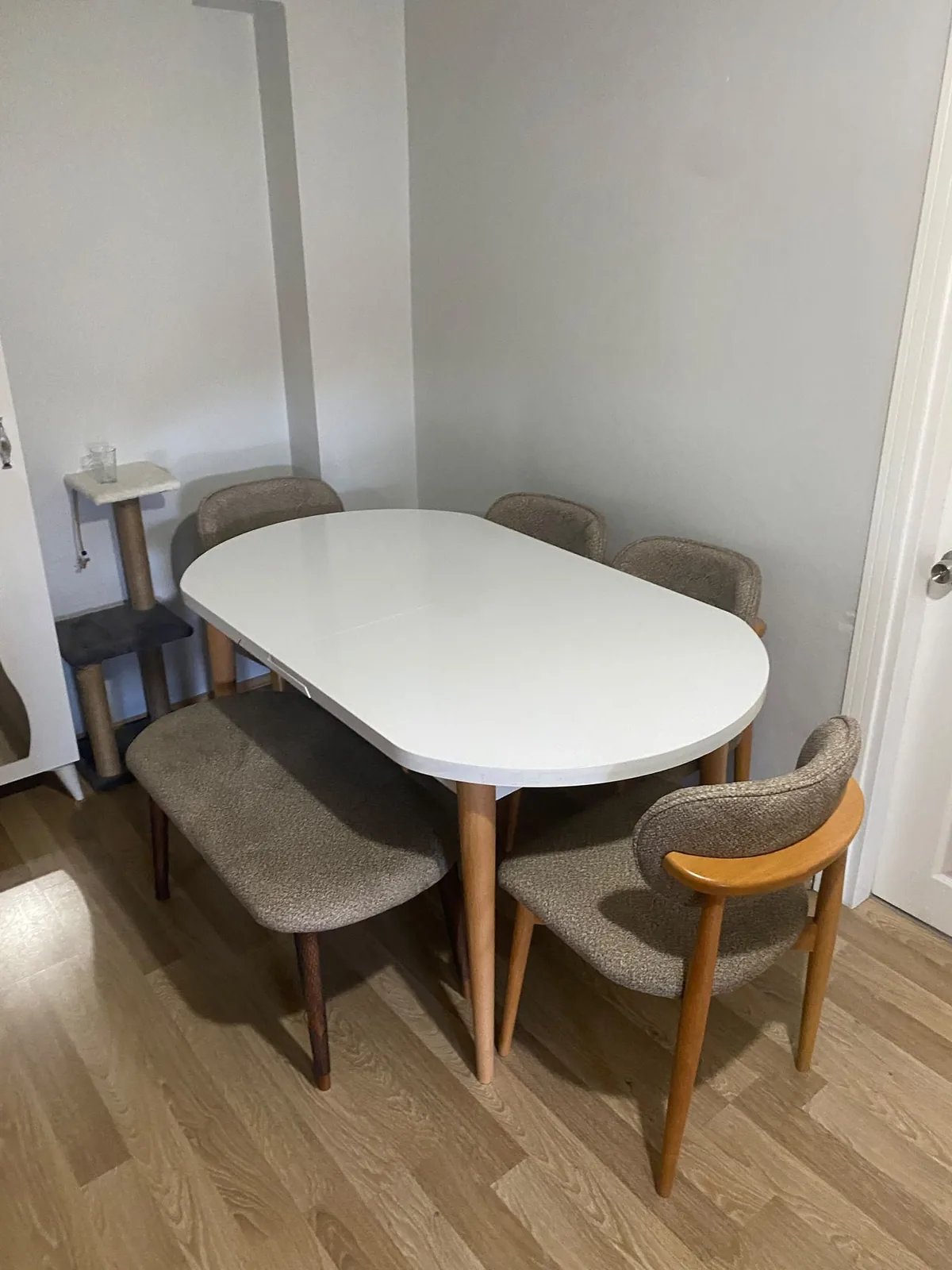 Beyaz oval açılır masa, bej bukle sandalyeler ve bench