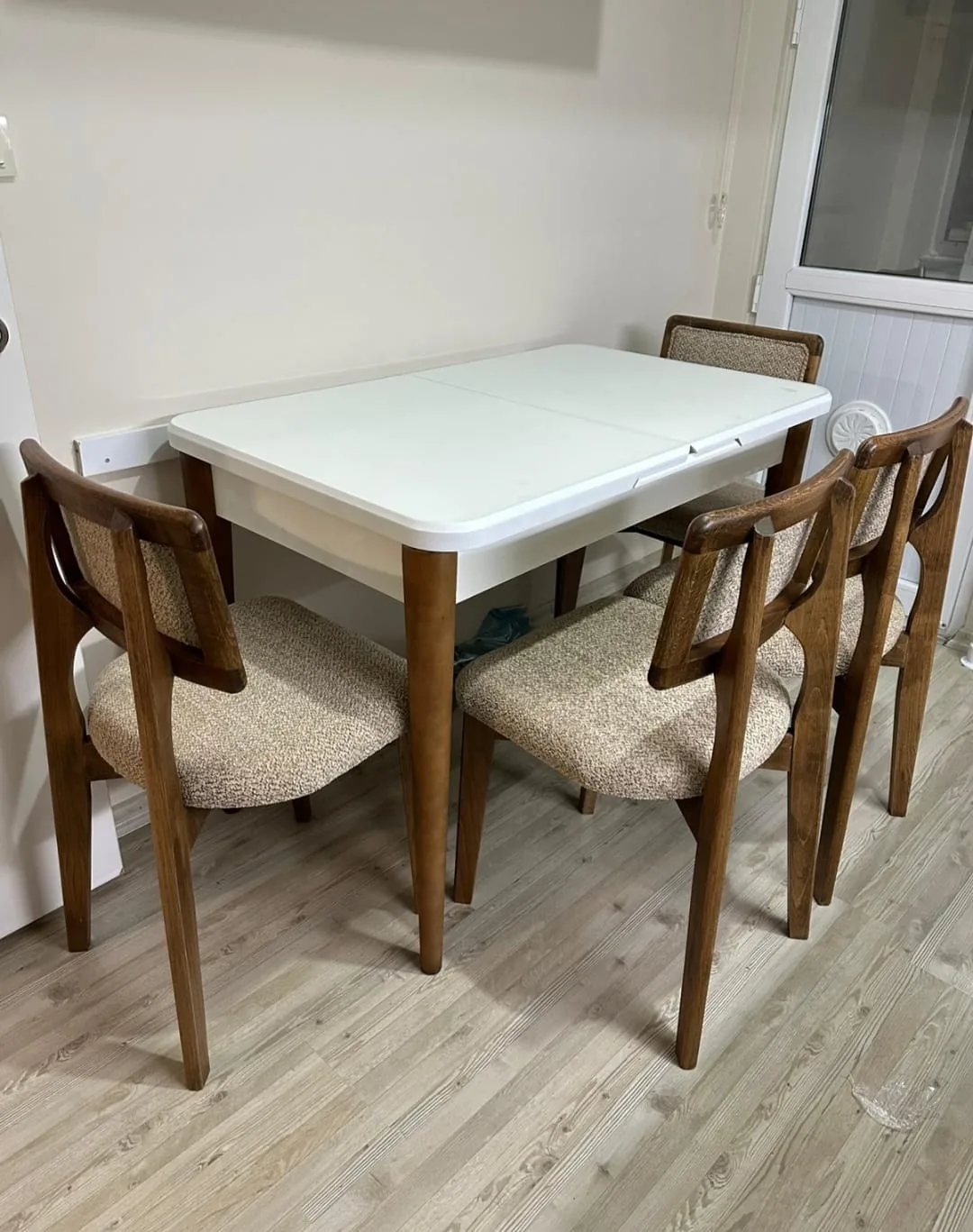 Beyaz açılır mutfak masası ve dört koyu ceviz ahşap sandalye