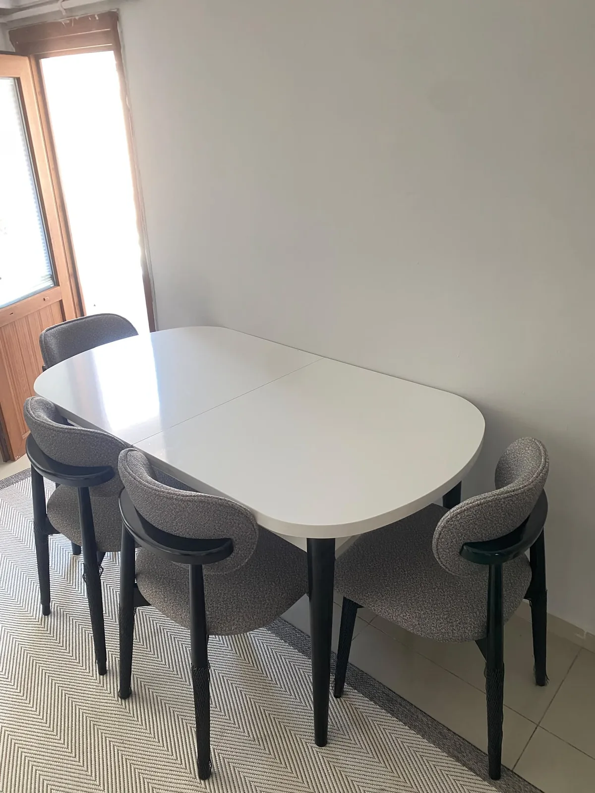 Beyaz oval açılır yemek masası ve dört gri bukle siyah ayaklı sandalye