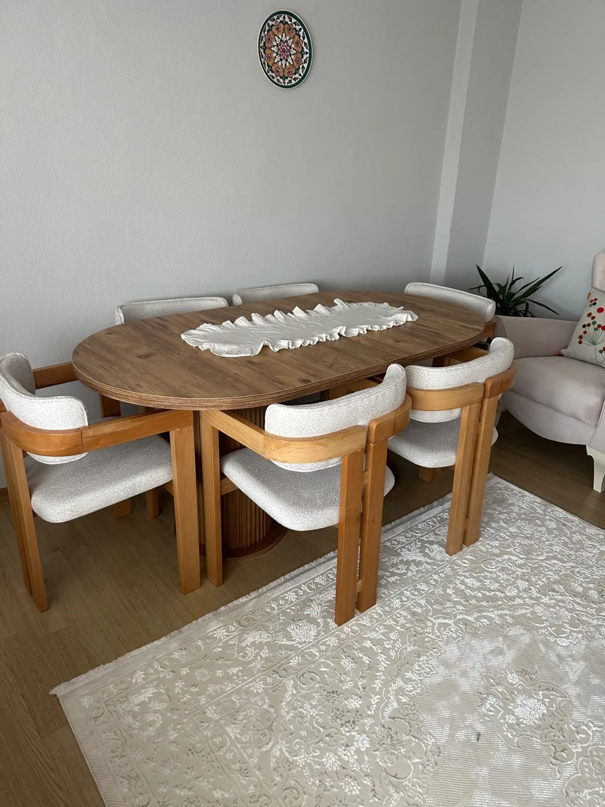 Salonda ceviz renk oval açılır masa ve altı krem bukle kollu sandalye