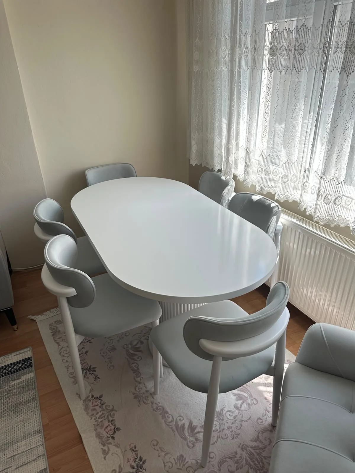 Beyaz oval açılır masa ve altı beyaz ayaklı gri deri sandalye